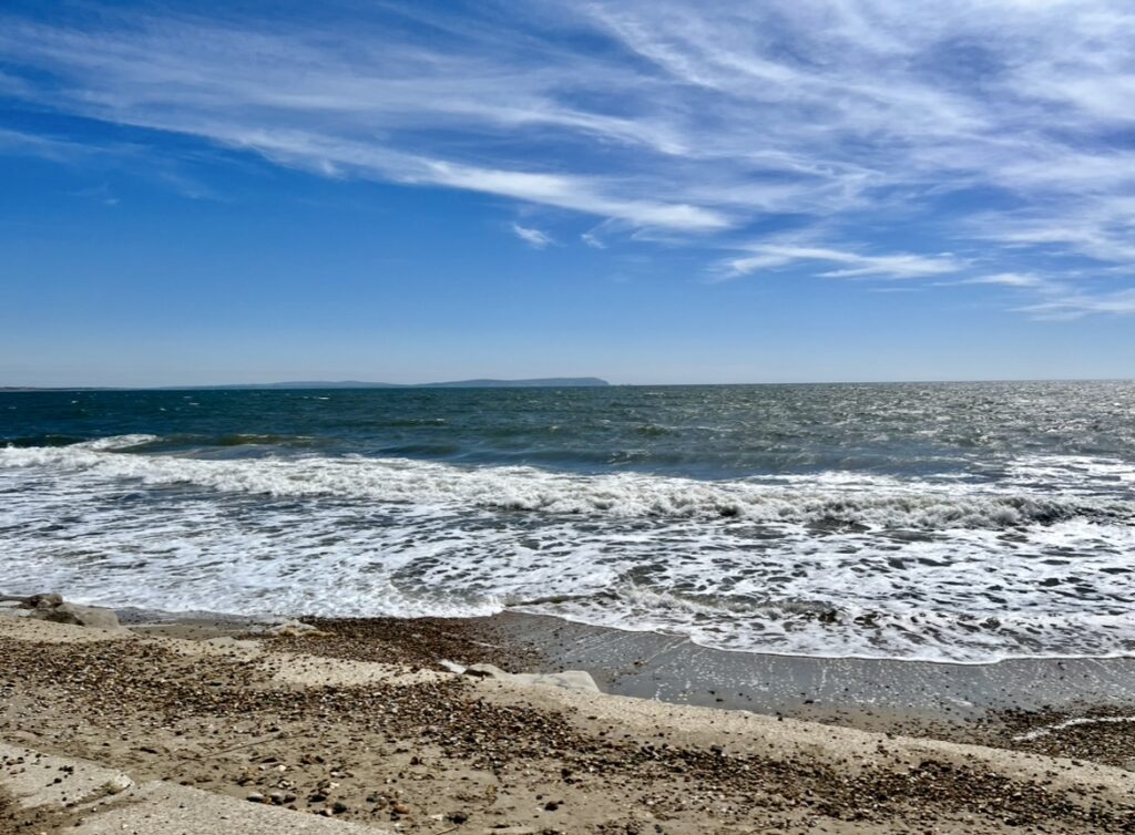 Seashore with waves and blue sky, symbolising calm and reflection on Michaela’s About Me page.