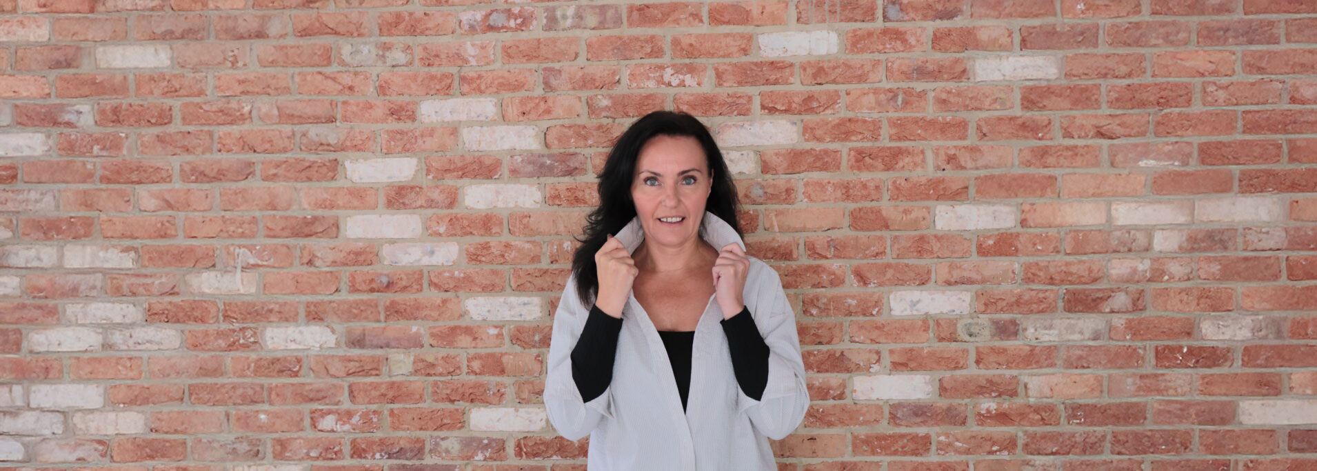 Portrait of Michaela, leadership and resilience coach, smiling confidently with hands on her collar.